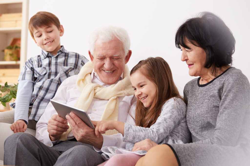 Happy grandparents and cute grandchildren using modern tablet for fun